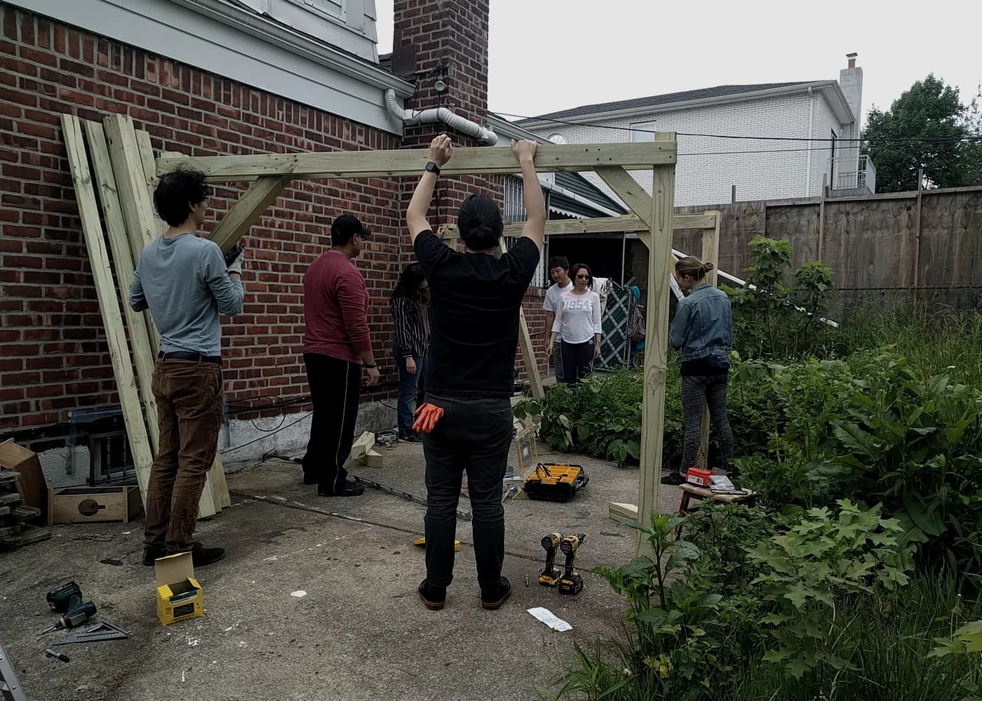 A group raising a timber frame in a backyard
