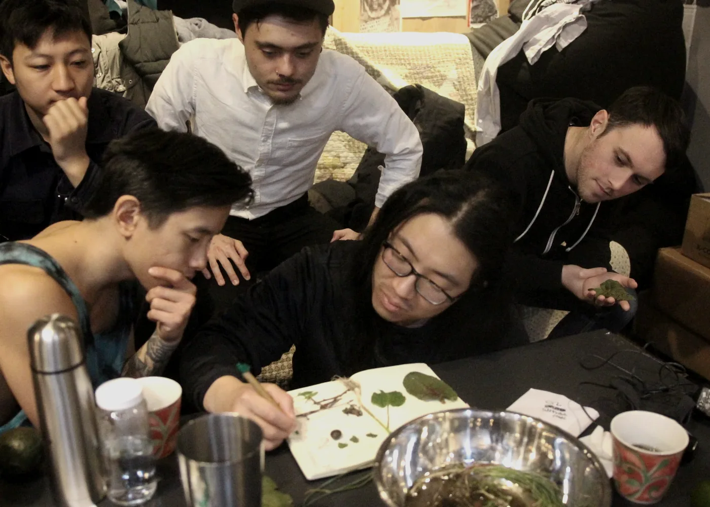 A group gathered around a table with notes and plants